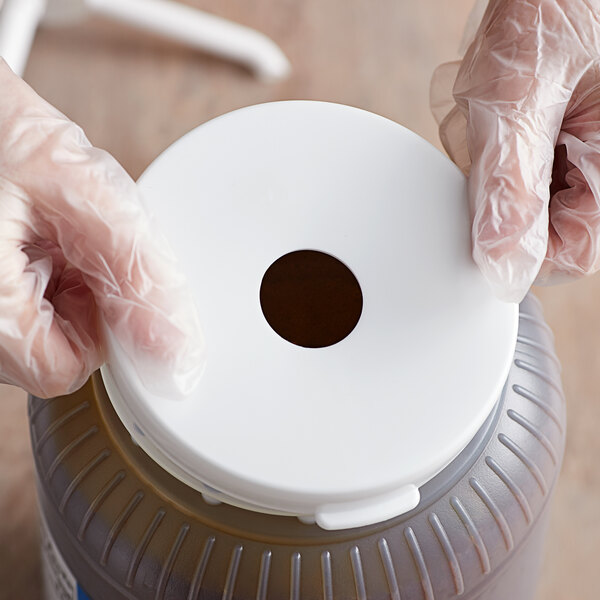 A person in gloves snapping a Tablecraft snap on adapter lid onto a white container.
