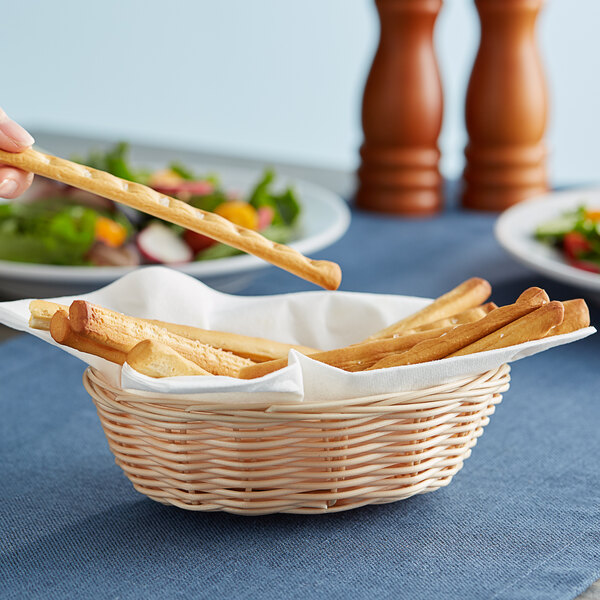 A person holding bread sticks in a Tablecraft oval basket.