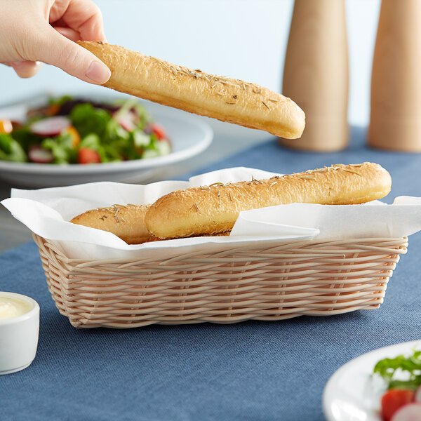 A person holding a baguette in a Tablecraft rectangle basket.