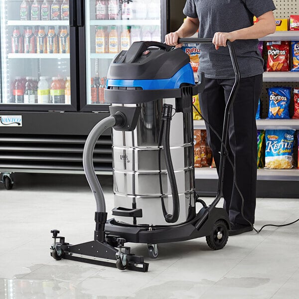 A person using a Lavex commercial wet/dry vacuum with squeegee tool.