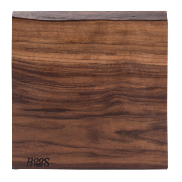 A John Boos black walnut wood cutting board with a rustic edge.
