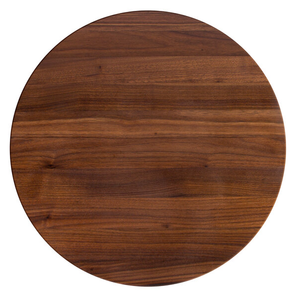 A John Boos black walnut round wood cutting board on a table.