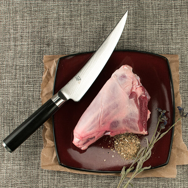 A piece of meat with spices being cut by a Shun Classic curved boning and fillet knife.