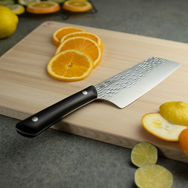 A Kai PRO Asian utility knife on a cutting board with sliced oranges.