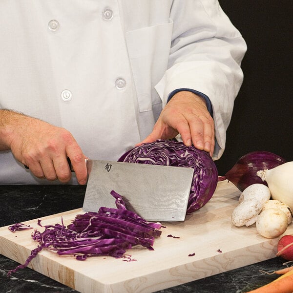 A chef using a Shun Classic Vegetable Cleaver to cut purple cabbage.