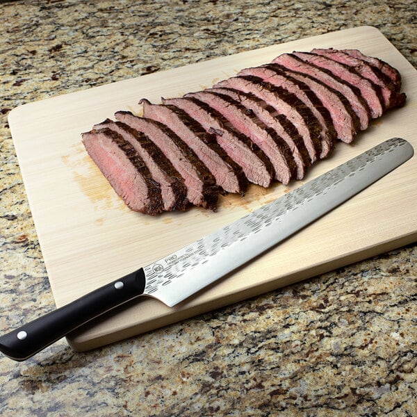 A Kai PRO slicing knife on a cutting board next to a sliced steak.