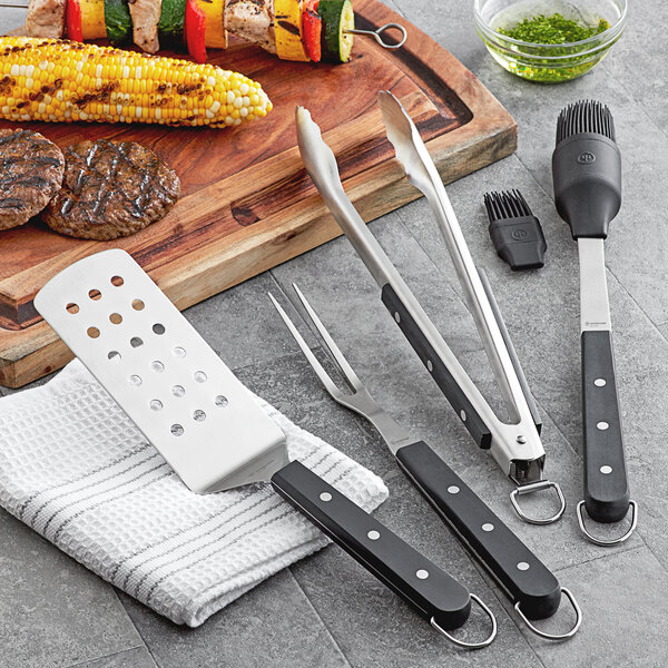 Wusthof barbecue tongs with black and white handles next to a fork and a knife.