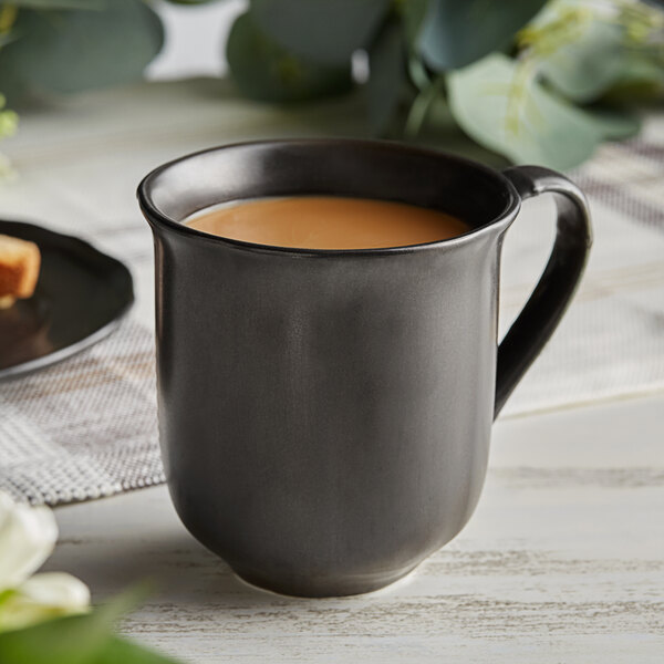 An Acopa Armor Gray porcelain mug filled with brown liquid on a table.