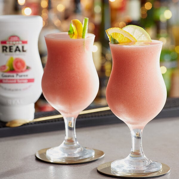Two glasses of pink drinks with lime slices, made with Real Guava Puree Infused Syrup.