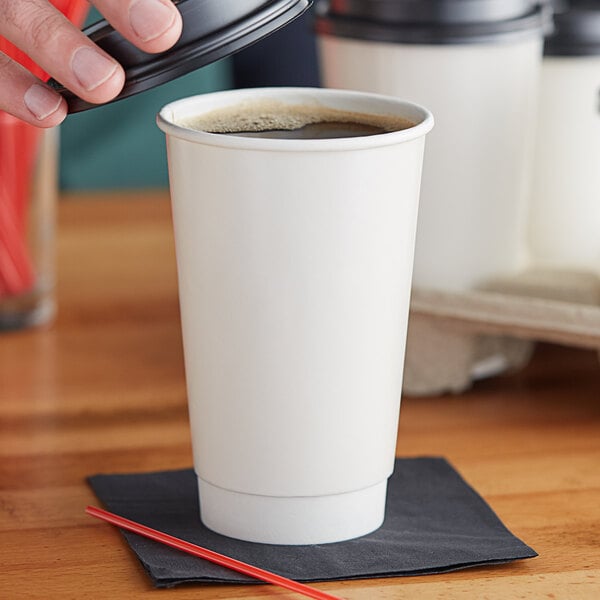 A person pouring a coffee into a white Choice paper cup.