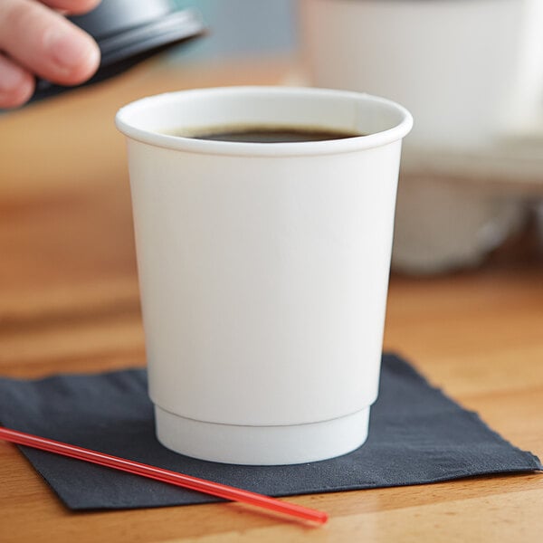 A person holding a Choice white paper hot cup of coffee with a straw.
