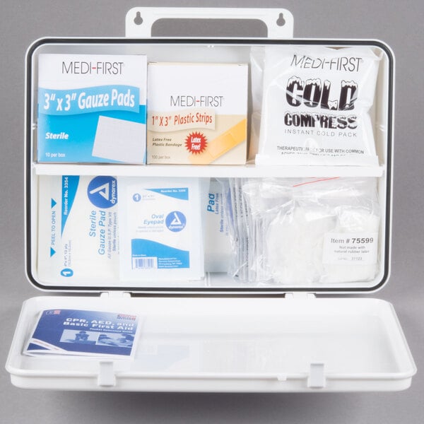 A white Medi-First first aid kit with supplies on a shelf.
