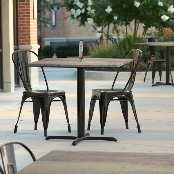 A Lancaster Table & Seating Excalibur square table with a textured metal finish on an outdoor patio.