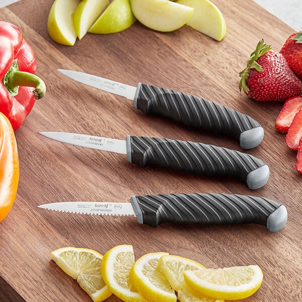 A Schraf paring knife set with TPRgrip handles on a wood surface with lemon slices.