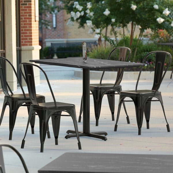 A Lancaster Table & Seating rectangular table with a smooth finish on an outdoor patio with chairs.