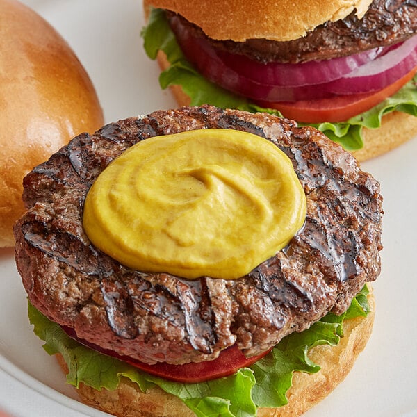 A plate of hamburgers with French's Yellow Mustard on top.