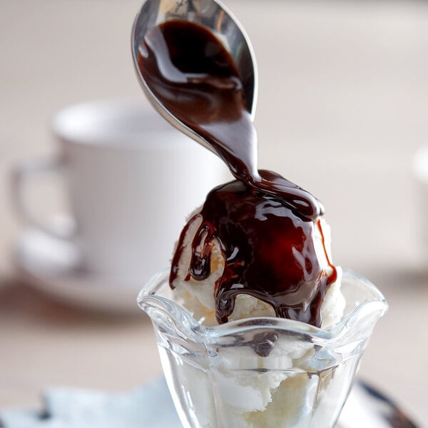 A spoon with J. Hungerford Smith Chocolate Fudge Topping on a dessert.