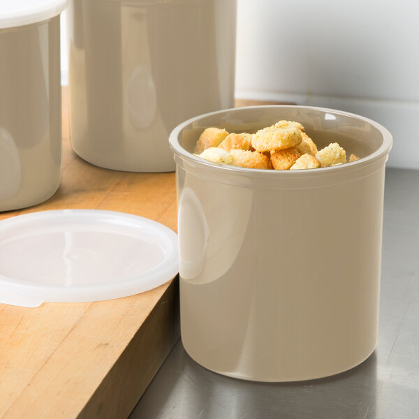 A beige Cambro round crock filled with food and a lid.