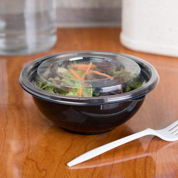 A Sabert FreshPack clear plastic lid on a bowl of salad with a plastic fork.