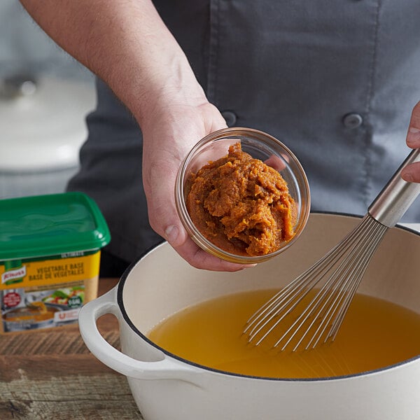 A person mixing Knorr Ultimate Vegetable Bouillon in a pot.