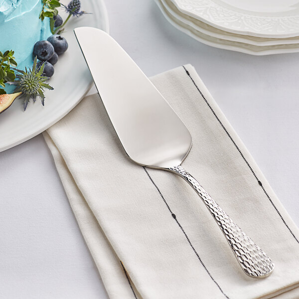 An Acopa stainless steel cake server on a napkin with a blueberry cake.