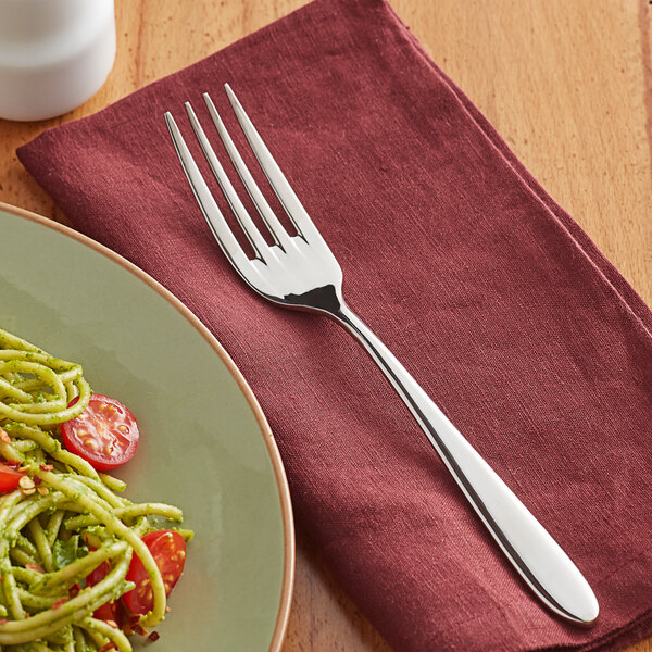 A Remy stainless steel dinner fork on a plate of pasta with tomatoes.