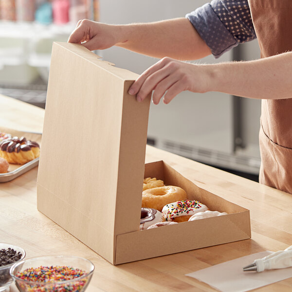 A woman opening a Baker's Mark Kraft bakery box of doughnuts.