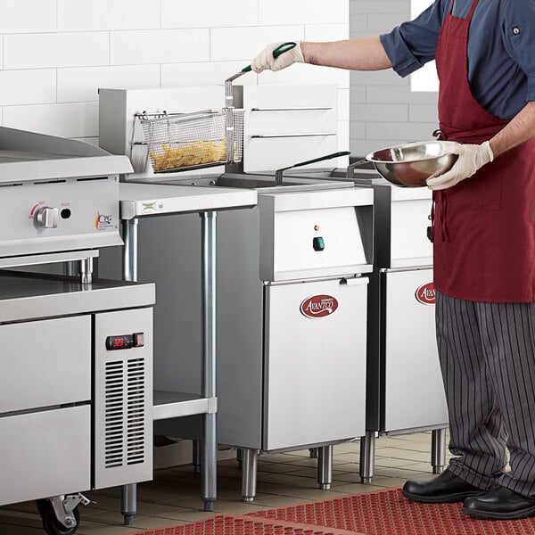 A man in a red apron using an Avantco electric floor fryer to cook food.