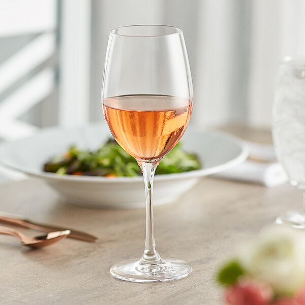 A Stolzle all-purpose wine glass filled with pink liquid on a table.