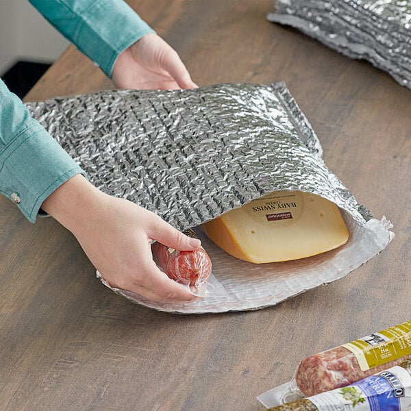 A person holding a Lavex foil bubble mailer filled with cheese and meat.