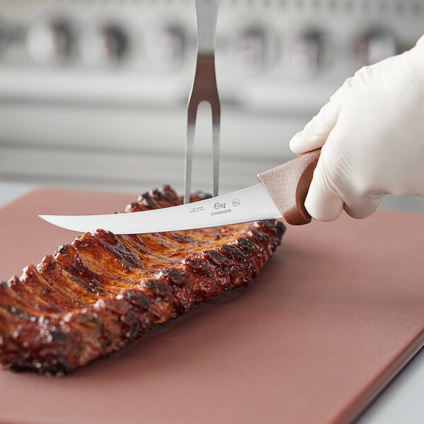 A gloved hand uses a Choice curved stiff boning knife with a brown handle to cut meat.