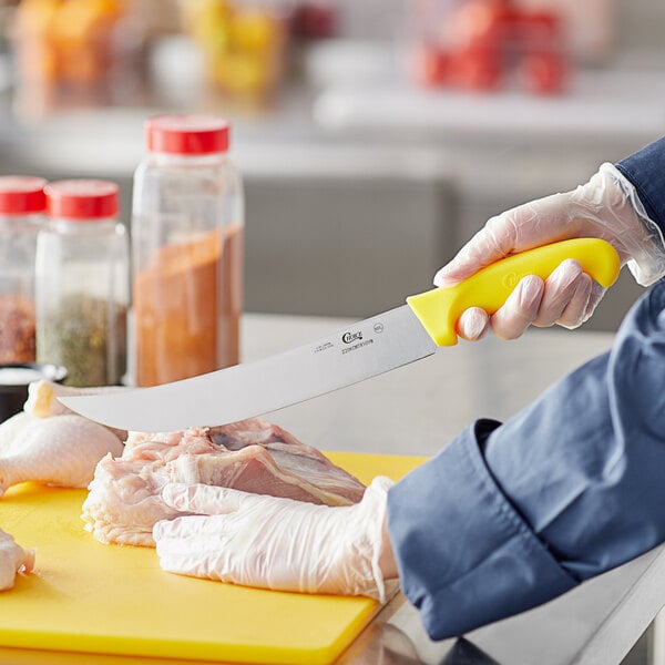 A person cutting meat with a Choice cimeter knife with a yellow handle.