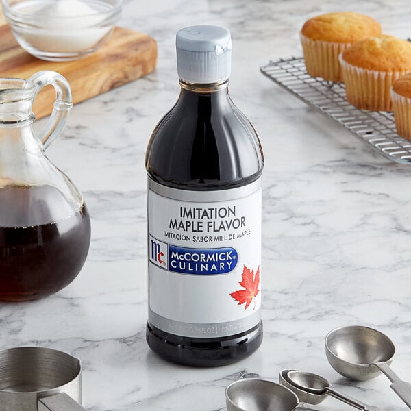 A bottle of McCormick Imitation Maple Extract on a counter next to a tray of muffins.