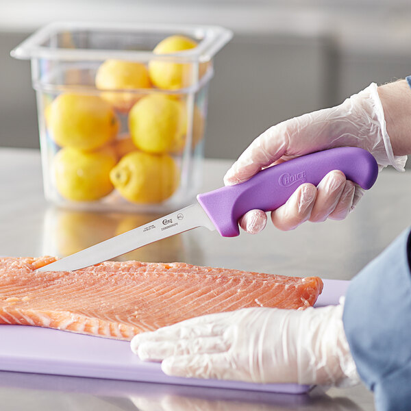 A person using a Choice narrow stiff boning knife to cut a piece of fish.