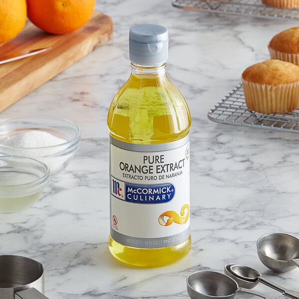 A bottle of McCormick Pure Orange Extract next to a tray of muffins.