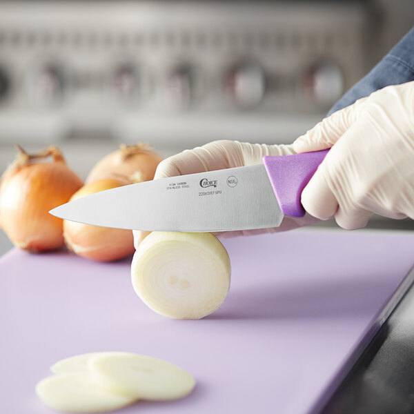 A person in gloves using a Choice chef knife to cut an onion.