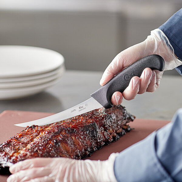 A person using a Choice curved boning knife to cut meat.