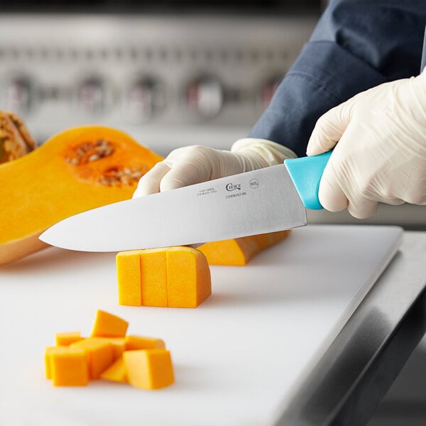 A person cutting a pumpkin with a Choice chef knife with a neon blue handle.
