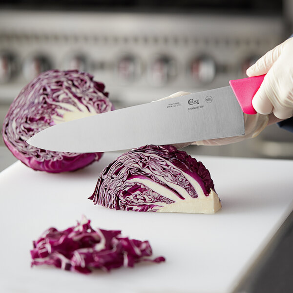 A person cutting cabbage with a Choice 10" chef knife with a neon pink handle.