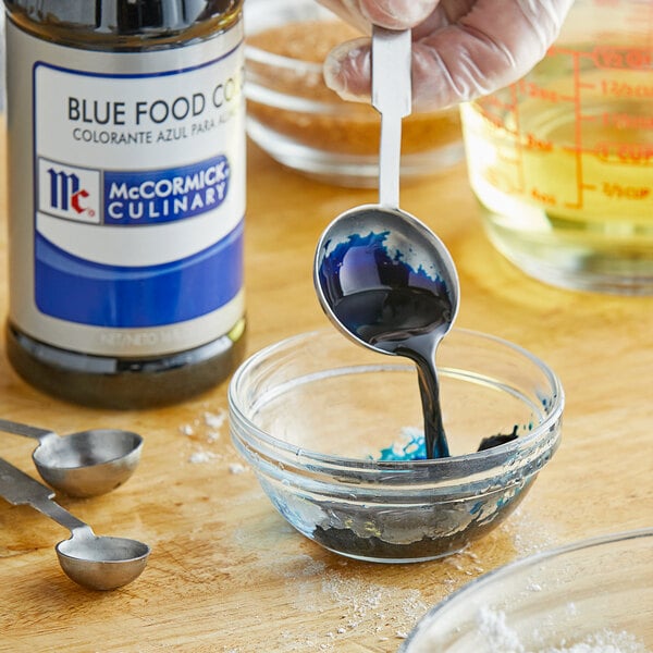A person pouring McCormick Culinary blue food color into a bowl.