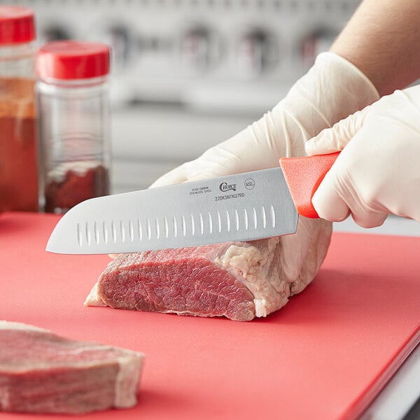 A person using a Choice Santoku knife with a red handle to cut meat.