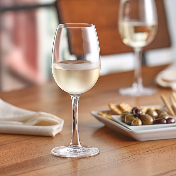 A Nude Reserva tall white wine glass filled with white wine on a table.
