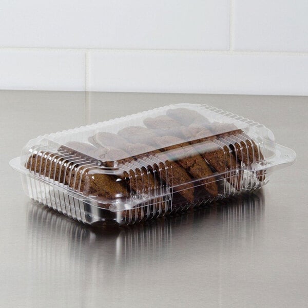 A Dart clear hinged PET plastic container of cookies on a bakery counter.