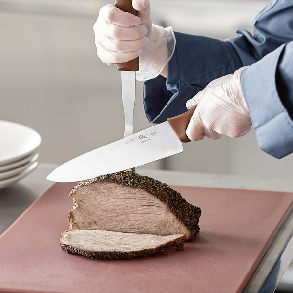 A person cutting meat with a Choice 8" Chef Knife.