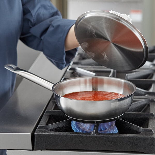 A woman cooking red sauce in a Vigor stainless steel saucier pan on a stove.