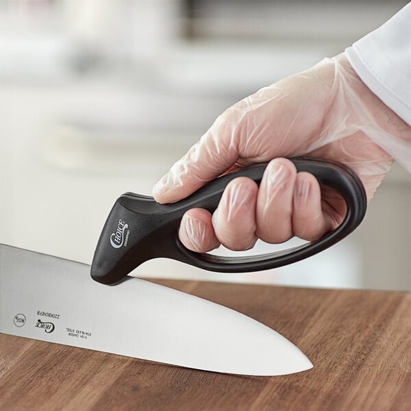A hand holding a black plastic-handled knife sharpening a knife.