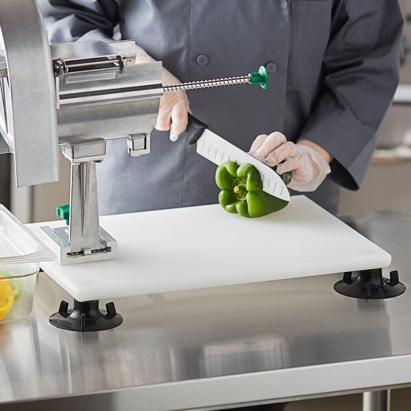 A person cutting a green bell pepper on a Garde rotary slicer mounted to a counter.