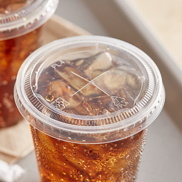 A plastic cup with a PLA compostable plastic lid and straw slot with a soda in it.
