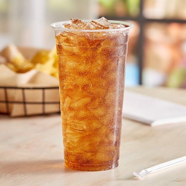 A cup of EcoChoice iced tea with a straw on a table in a fast food restaurant.