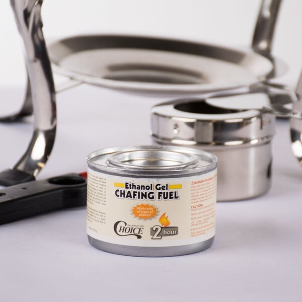 A 12 pack of Choice ethanol gel chafing dish fuel cans on a table next to a metal pot.